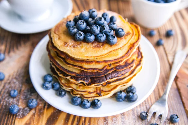 Pfannkuchen gesundes Frühstück mit Blaubeeren, Moorhuhn, Tasse grünem Tee, Tasse Blaubeeren und Teekanne auf braunem Holzgrund — Stockfoto