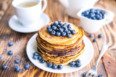 Yaban mersini, bataklık whortleberry, yeşil çay, yaban mersini ve çaydanlık kahverengi ahşap zemin üzerinde kupa ile sağlıklı kahvaltı krep 