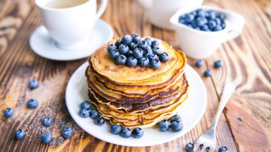 Yaban mersini, bataklık whortleberry, yeşil çay, yaban mersini ve çaydanlık kahverengi ahşap zemin üzerinde kupa ile sağlıklı kahvaltı krep 