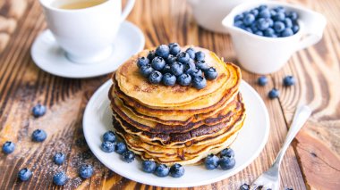 Yaban mersini, bataklık whortleberry, yeşil çay, yaban mersini ve çaydanlık kahverengi ahşap zemin üzerinde kupa ile sağlıklı kahvaltı krep 