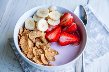 Sağlıklı kahvaltı dahil mısır gevreği ve oatflakes, yoğurt, muz ve çilek
