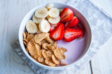 Sağlıklı kahvaltı dahil mısır gevreği ve oatflakes, yoğurt, muz ve çilek