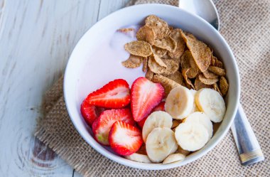 Sağlıklı kahvaltı dahil mısır gevreği ve oatflakes, yoğurt, muz ve çilek