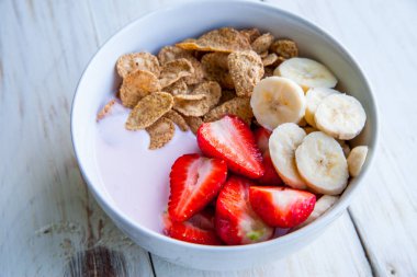 Sağlıklı kahvaltı dahil mısır gevreği ve oatflakes, yoğurt, muz ve çilek