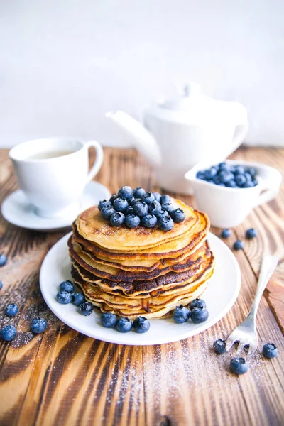 건강 한 아침 블루베리, 늪지 whortleberry, 녹차의 컵, 컵 블루베리와 갈색 나무 배경에 주전자의 팬케이크 — 스톡 사진