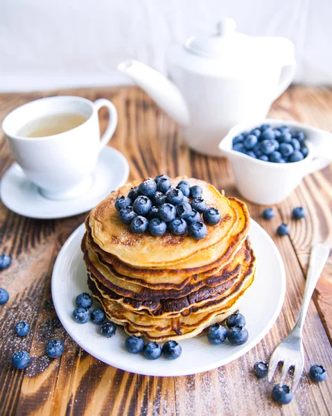 Pfannkuchen gesundes Frühstück mit Blaubeeren, Moorhuhn, Tasse grünem Tee, Tasse Blaubeeren und Teekanne auf braunem Holzgrund — Stockfoto