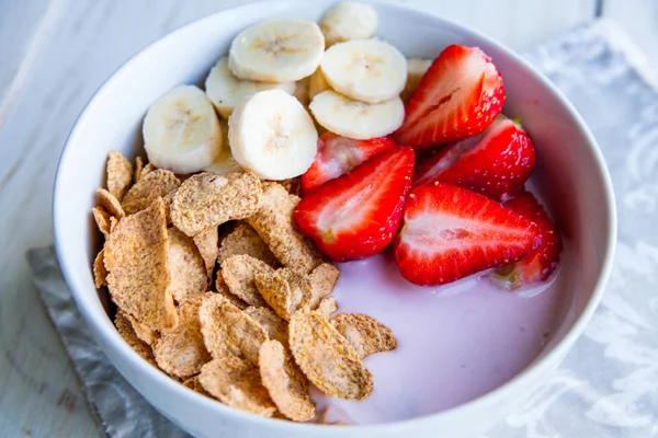Sağlıklı kahvaltı dahil mısır gevreği ve oatflakes, yoğurt, muz ve çilek