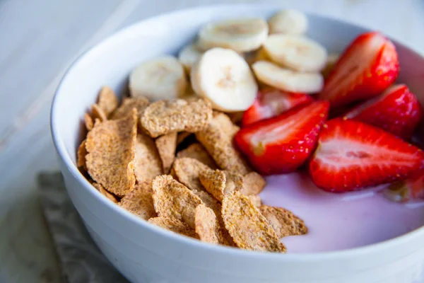 Sağlıklı kahvaltı dahil mısır gevreği ve oatflakes, yoğurt, muz ve çilek