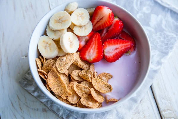 Sağlıklı kahvaltı dahil mısır gevreği ve oatflakes, yoğurt, muz ve çilek