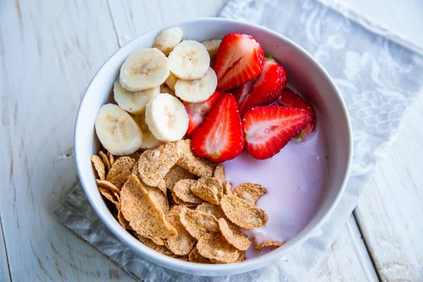 Sağlıklı kahvaltı dahil mısır gevreği ve oatflakes, yoğurt, muz ve çilek