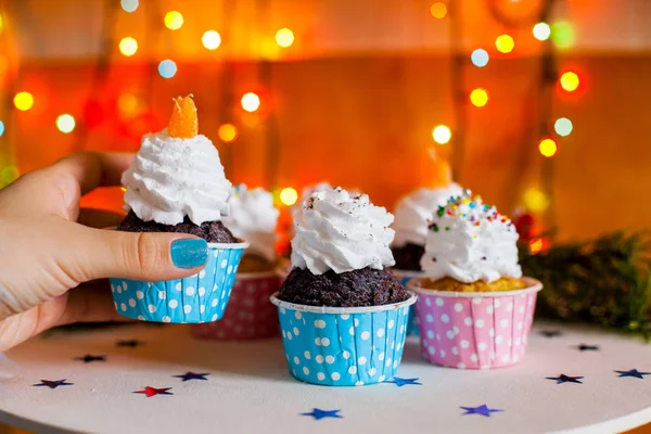 Christmas cupcakes with light, wooden background, stars, and christmas tree