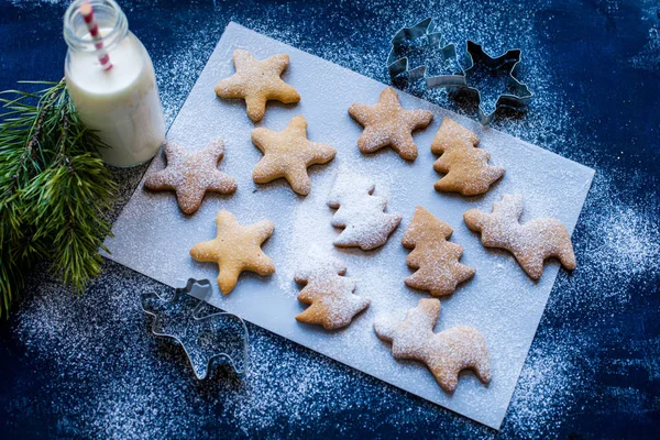 Noel kurabiyeleri, çerez kesici, şişe süt ve mavi ahşap arka plan üzerinde Noel ağacı 