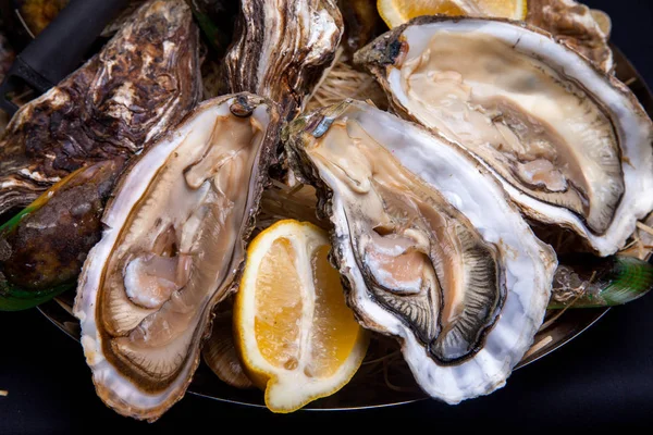 Öppnade ostron på Folkmusik inredda plattan med citron och oyster kniv i restaurang utfodring med ros champagne — Stockfoto