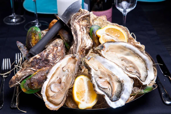 Öppnade ostron på Folkmusik inredda plattan med citron och oyster kniv i restaurang utfodring med ros champagne — Stockfoto