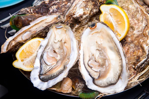 Öppnade ostron på Folkmusik inredda plattan med citron och oyster kniv i restaurang utfodring med ros champagne — Stockfoto