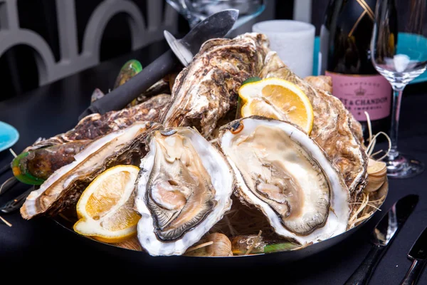 Öppnade ostron på Folkmusik inredda plattan med citron och oyster kniv i restaurang utfodring med ros champagne — Stockfoto