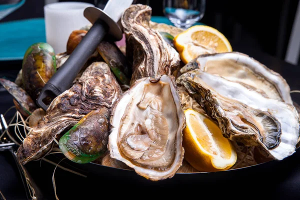 Öppnade ostron på Folkmusik inredda plattan med citron och oyster kniv i restaurang utfodring med ros champagne — Stockfoto