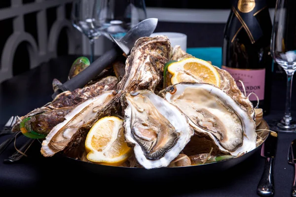 Öppnade ostron på Folkmusik inredda plattan med citron och oyster kniv i restaurang utfodring med ros champagne — Stockfoto