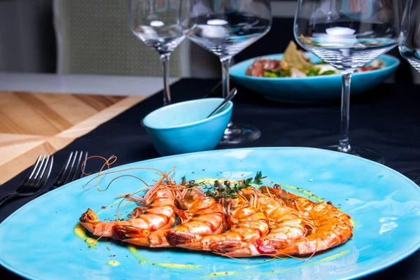 Camarones a la parrilla con romero en el plato azul servido en el restaurante con sous y vino — Foto de Stock