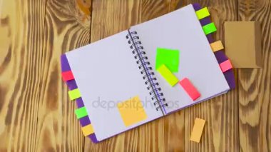 Marker düşüyor tablo / ahşap arka plan. Ofis, banka donatımı ile açık not etmek. Marker, kalem, kalem ve çıkartmaları ile ahşap bir masaüstünde açık not defteri yatıyor