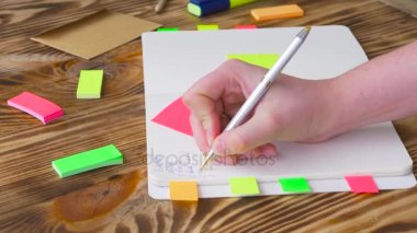 Kadın Notlar not defteri yazın. Ofis, banka donatımı ile açık not etmek. Marker, kalem, kalem ve çıkartmaları ile ahşap bir masaüstünde açık not defteri yatıyor