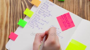 Kadın Notlar not defteri yazın. Ofis, banka donatımı ile açık not etmek. Marker, kalem, kalem ve çıkartmaları ile ahşap bir masaüstünde açık not defteri yatıyor