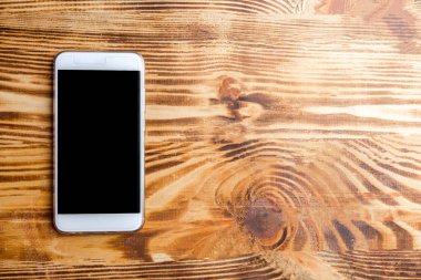 Not defteri ve kalem ile koyu ahşap arka plan üstünde hareket eden telefon