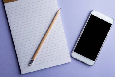 Not defteri ve kalem mor zemin üzerine beyaz cep telefonu