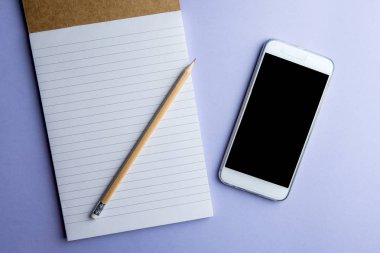 Not defteri ve kalem mor zemin üzerine beyaz cep telefonu