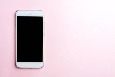 Pembe bir arka plan üzerinde beyaz cep telefonu. Kopya alanı, üstten görünüm