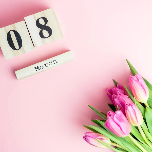 Mutlu kadın 8 Mart günü kavramı. Ahşap blok takvim ve Pembe Lale ile pembe bir arka plan üzerinde