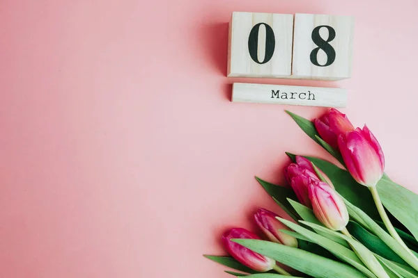 Mutlu kadın 8 Mart günü kavramı. Ahşap blok takvim ve Pembe Lale ile pembe bir arka plan üzerinde