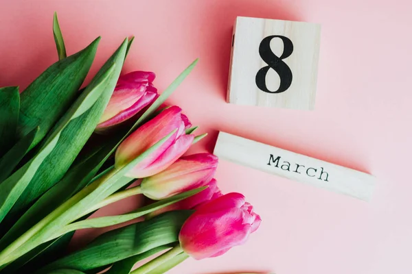 Mutlu kadın 8 Mart günü kavramı. Ahşap blok takvim ve Pembe Lale ile pembe bir arka plan üzerinde