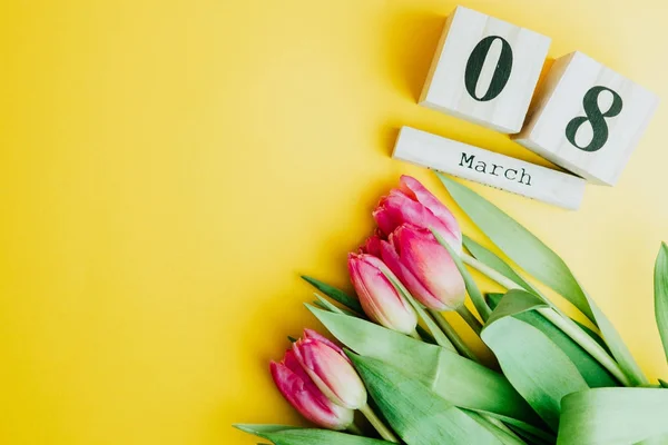 Mutlu kadın 8 Mart günü kavramı. Ahşap blok takvim ve Pembe Lale ile sarı zemin üzerine. Kopya alanı