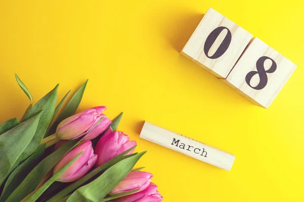 8 March Happy Women\'s Day concept. With wooden block calendar and pink tulips on yellow background. Copy space