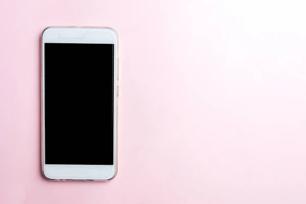 Pembe bir arka plan üzerinde beyaz cep telefonu. Kopya alanı, üstten görünüm