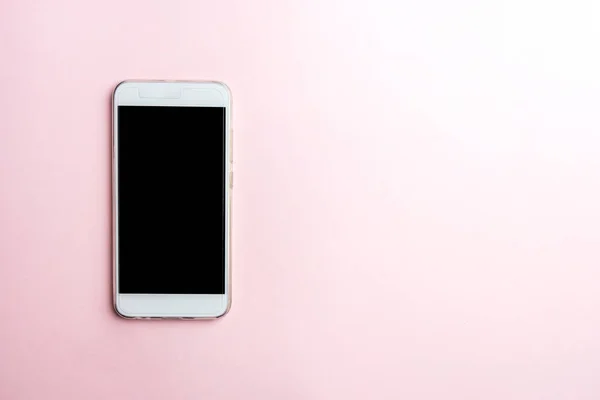Pembe bir arka plan üzerinde beyaz cep telefonu. Kopya alanı, üstten görünüm