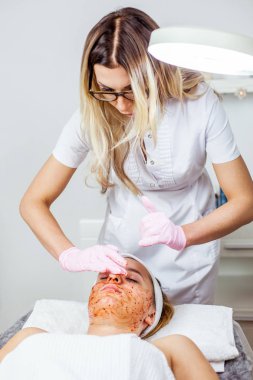 Güzellik uzmanı yüz maskesi, spa güzellik bakımı genç kız için peeling yapıyor. Model, yakın çekim. Kosmetoloji Kliniği. Sağlık