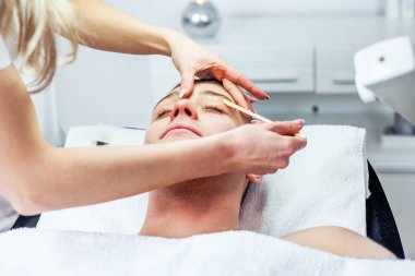 Güzellik uzmanı kadın kaş modelleme için cımbız adam yapıyor. Kosmetoloji Kliniği. Sağlık