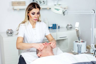 Güzellik uzmanı yordamı yüz masaj genç için yapıyor oğlum / dostum. Model, yakın çekim. Kosmetoloji Kliniği. Sağlık