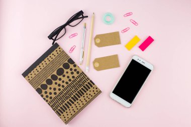 Yaratıcı düz fotoğraf çalışma masası smartphone, gözlük, kalem, kurşun kalem ve defter, pembe bir arka plan üzerinde en az tarzı yatırın. En az iş kavramı