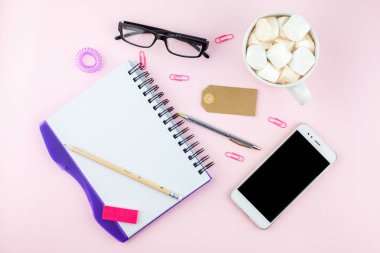 Yaratıcı düz fotoğraf çalışma masası smartphone, gözlük, kalem, kurşun kalem ve defter, pembe bir arka plan üzerinde en az tarzı yatırın. En az iş kavramı
