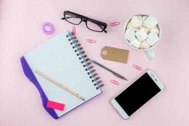 Yaratıcı düz fotoğraf çalışma masası smartphone, gözlük, kalem, kurşun kalem ve defter, pembe bir arka plan üzerinde en az tarzı yatırın. En az iş kavramı