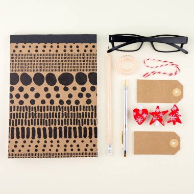 Yaratıcı düz fotoğraf çalışma masası gözlük, kalem, kurşun kalem ve defter, en az tarzı krem zemin üzerine yatırın. Etiketler ve Noel dekorasyonu ile en az Chtistmas alışveriş kavramı