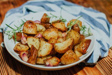 Biberiye ve sarımsak ile ahşap arka plan üzerinde beyaz tabak içinde kavrulmuş patates