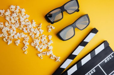 Sinema en az kavramı. Sinemada film izlemek. 3D gözlük, patlamış mısır, Sarı zemin üzerine clapper kurulu 
