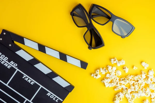 Sinema en az kavramı. Sinemada film izlemek. 3D gözlük, patlamış mısır, Sarı zemin üzerine clapper kurulu 