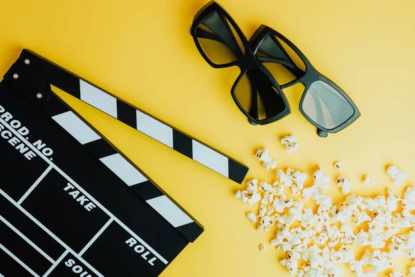 Cinema minimal concept. Watching film in the cinema. 3d glasses, popcorn, clapper board on yellow background