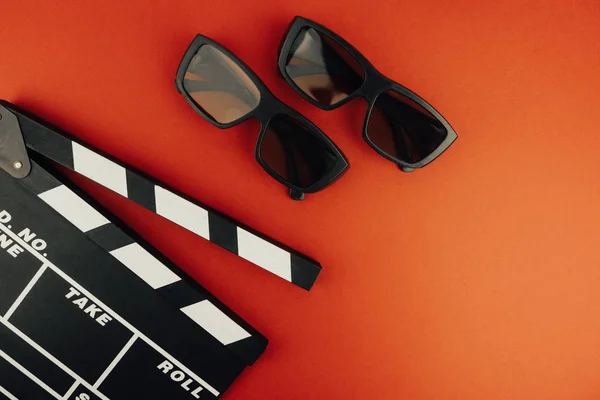 Sinema en az kavramı. Sinemada film izlemek. Clapper kurulu, 3d gözlük, kırmızı zemin üzerine. 
