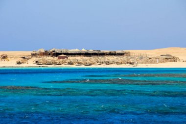 Sarı kum plajı ile deniz manzarası.